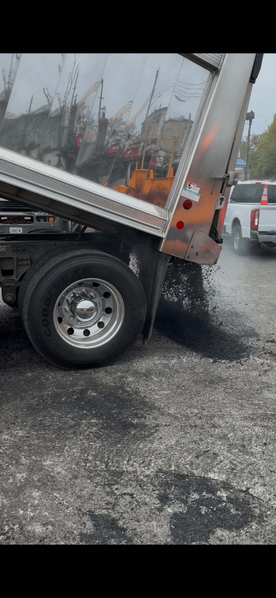 Asphalt Co dump truck unloading fresh hot mix asphalt at a job site
