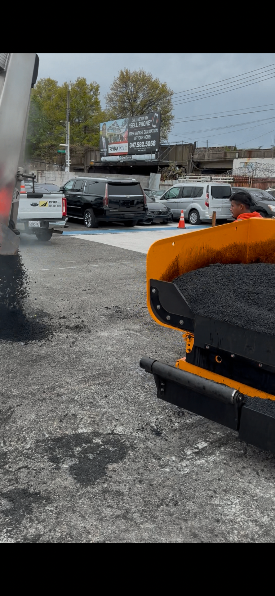 Asphalt Co paver laying a fresh mat of hot asphalt on a commercial lot